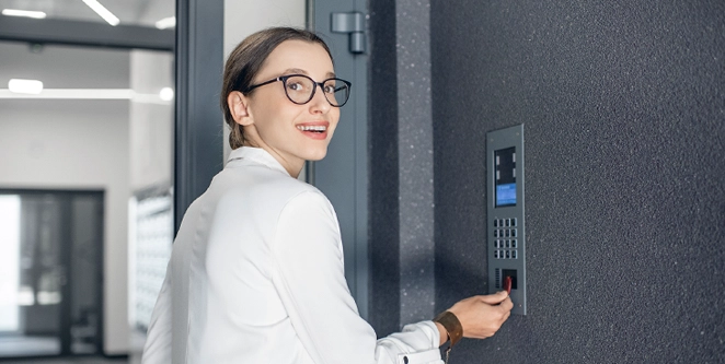 Kvinna i utvändig entrémiljö som får access med sin tagg via fastighetens passersystem
